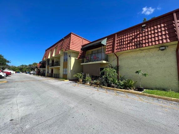 Front view of a multi-story apartment building with a red-tiled roof.
