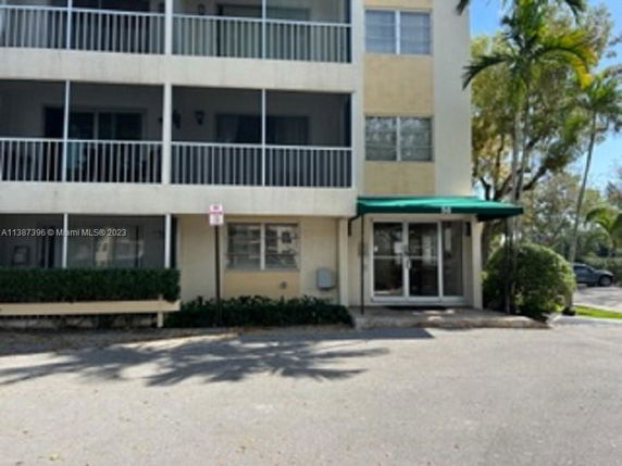 Front view of a multi-story building with balconies and a green awning over the entrance.