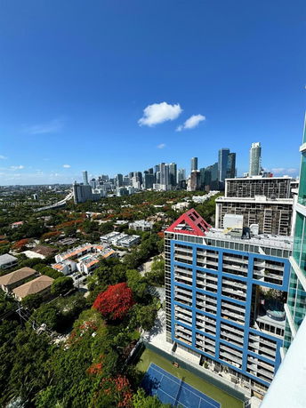Wide angle view of a cityscape with tall buildings and a tennis court on the lower right.