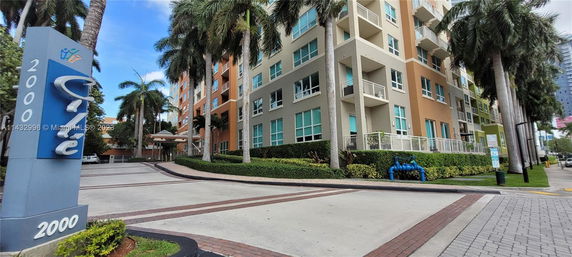 Front view of a multi-story residential building with balconies and a driveway.
