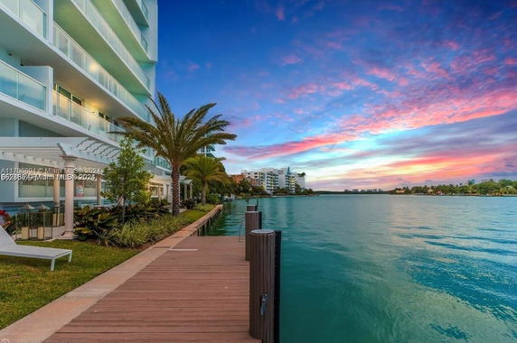 View of waterfront area with residential building and boardwalk.