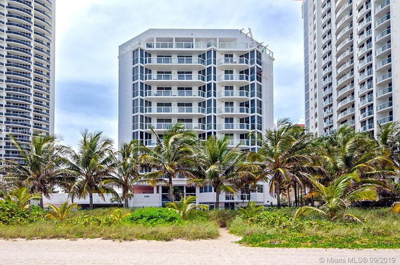 Front view of a multi-story condominium building with balconies and large windows.