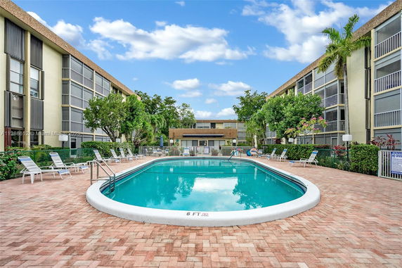 Outdoor swimming pool surrounded by multi-story residential buildings.