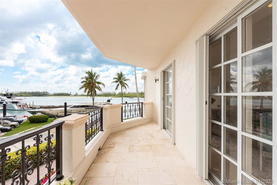 Balcony view with glass doors overlooking water and palm trees.