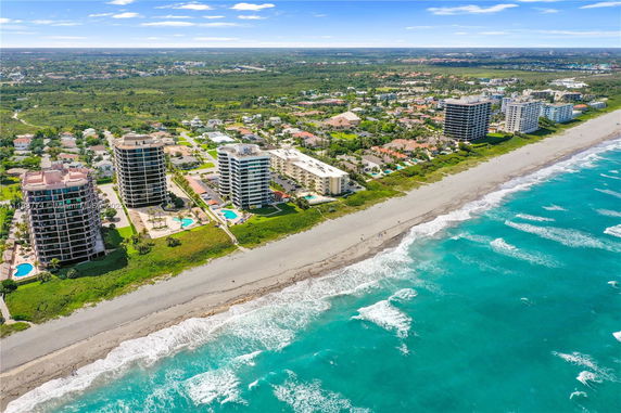 Aerial view of beachfront high-rise buildings with swimming pools and surrounding residential area.