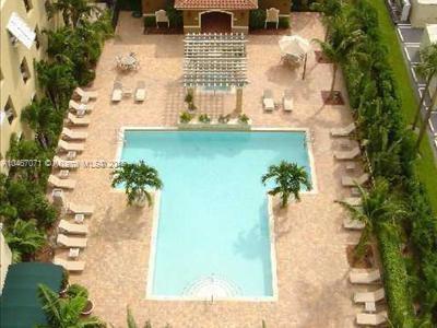 Top view of an outdoor swimming pool surrounded by lounge chairs and palm trees.