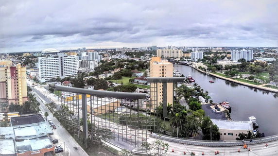 Wide view of a cityscape with buildings, roads, and a river.