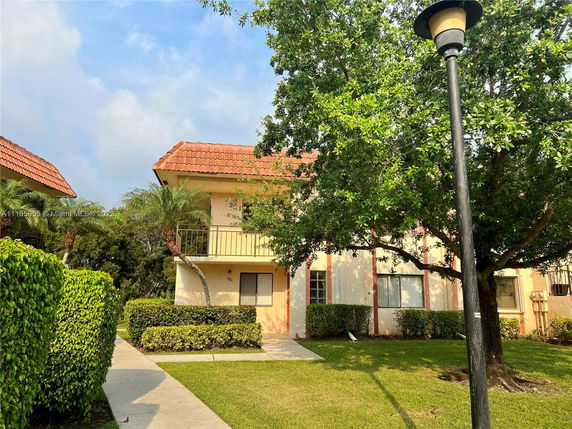 Front view of a two-story building with red-tiled roof and balcony.