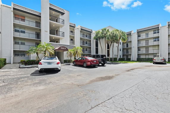 Front view of a multi-story residential building with parking area.