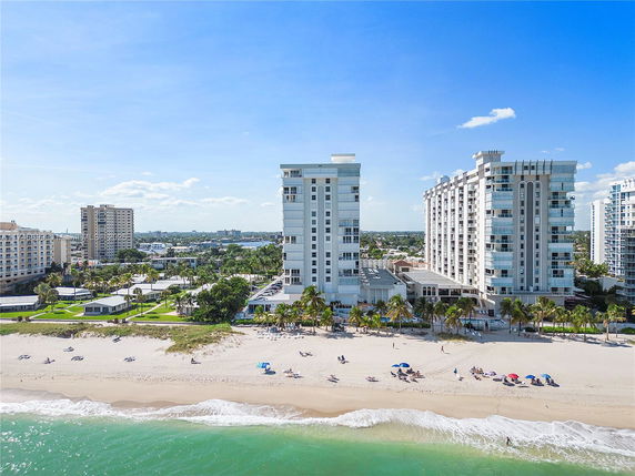 Coastal high-rise buildings near a sandy beach with people and umbrellas.