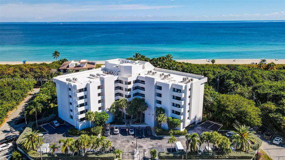 Front view of a multi-story white building by the beach.