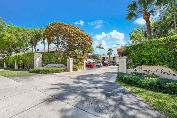 Entrance view of Monterey Gardens with a gated entryway and parking area.