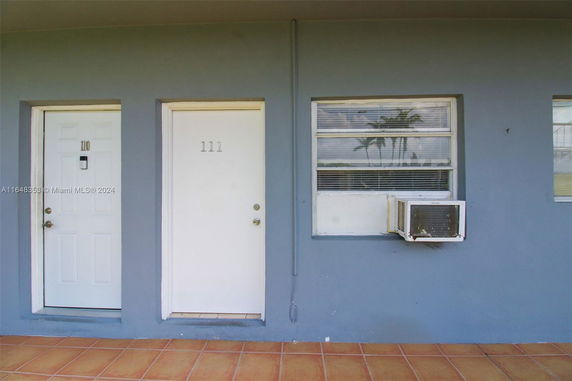 Front view of a building with numbered doors and a window air conditioning unit.