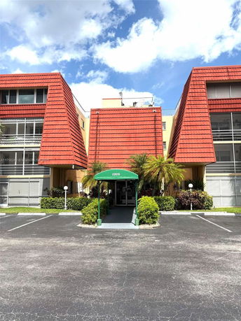 Front view of a multi-story building with red roof and green entrance canopy.