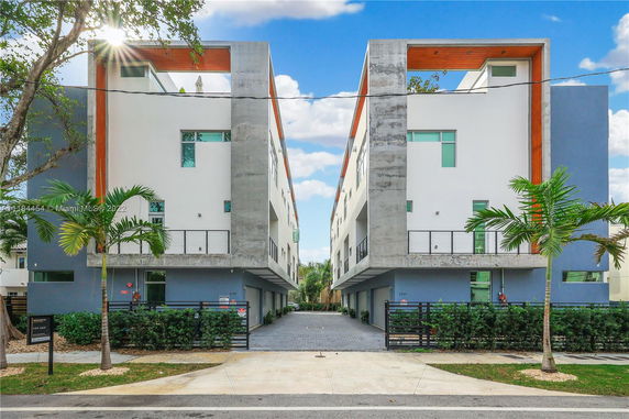 Front view of a modern multi-story building with a central open driveway.
