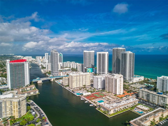 Aerial view of high-rise buildings along a waterway with the ocean in the background.