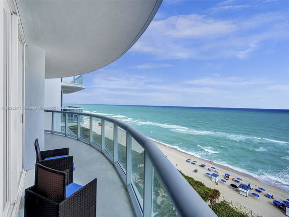 View from a building balcony overlooking the ocean and beach.