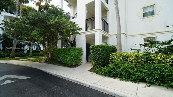 Front view of a multi-story building with balconies and surrounding greenery.