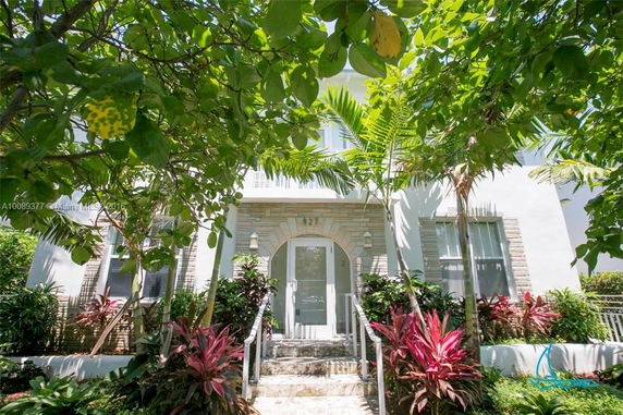 Front view of a two-story house with white exterior and arched entrance.
