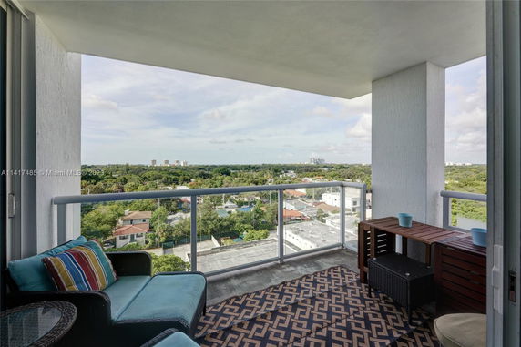 Balcony view overlooking a green landscape with buildings in the distance.