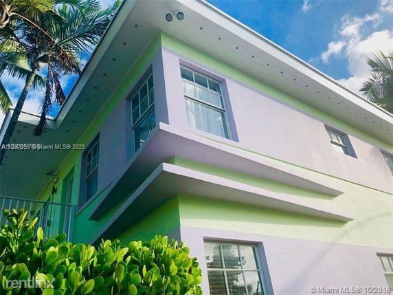 Exterior view of a two-story building with pastel green and purple walls and large windows.