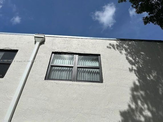 View of a wall with two windows and a drainpipe.