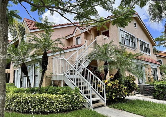 Front view of a house with an exterior staircase and red-tiled roof.