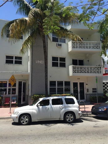 Front view of a multi-story building with balconies and palm trees.