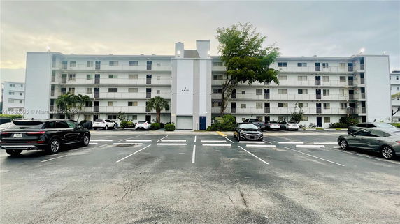 Front view of a multi-story residential building with a parking area in front.