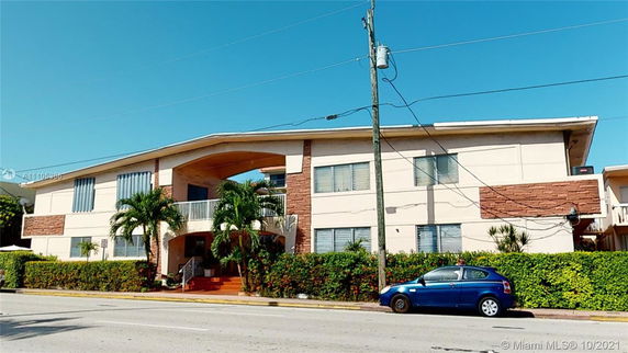 Front view of a two-story building with a distinct entrance and greenery.