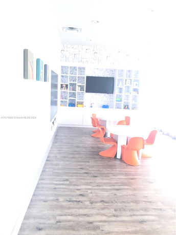 Room with modern children's play area featuring orange chairs and a screen.