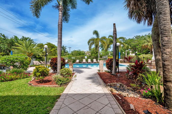 Outdoor swimming pool area with surrounding palm trees and seating.