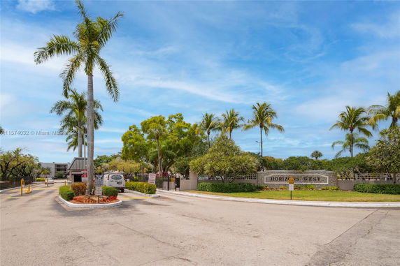 Entrance view of a residential complex with palm trees.
