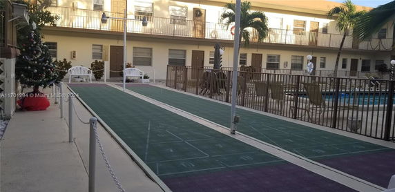 Outdoor recreational area with shuffleboard courts and a fenced pool.