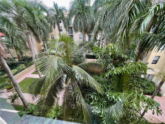 View of apartment buildings surrounded by palm trees and a courtyard area.