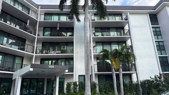 Front view of a multi-story residential building with balconies and a covered entrance.