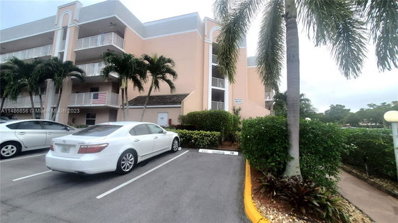 Front view of a multi-story building with balconies and a parking area.
