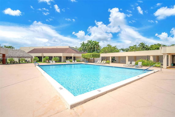 Outdoor swimming pool with surrounding seating area and adjacent building.