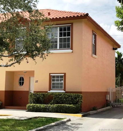 Front view of a two-story house with a terracotta tiled roof and beige exterior walls.
