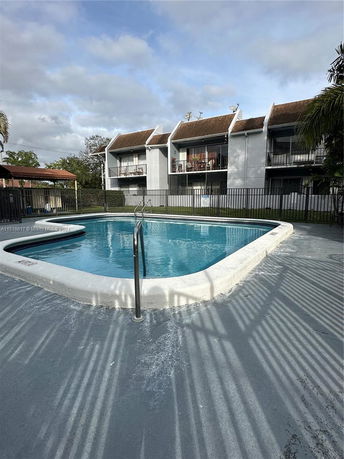 View of a swimming pool in front of a two-story residential building.