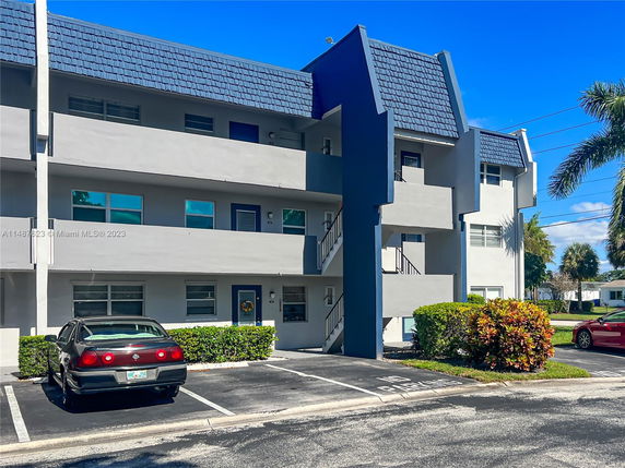 Front view of a multi-story apartment building with parking spaces in front.