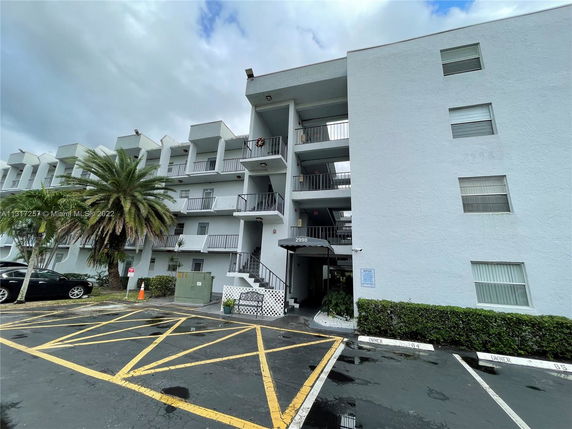 Front view of a multi-story building with balconies and parking area.