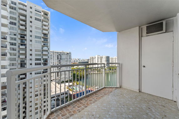 High-rise balcony view of surrounding high-rise buildings and a water body.