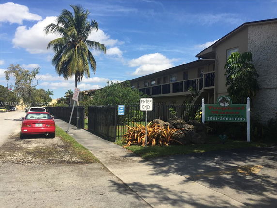 Front view of a multi-story condominium building with a sign reading 'Tropical Manor Condominiums'.