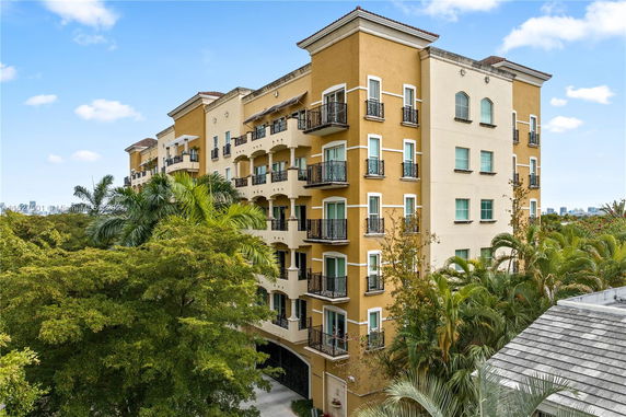 Front view of a multi-story building with multiple balconies and yellow facade.