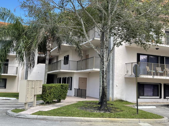 Front view of a multi-story building with balconies and parking area.