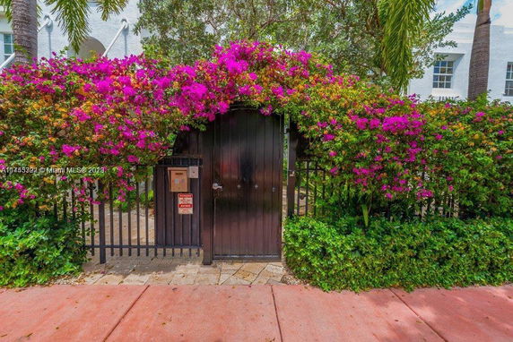 Front view of a building entrance with a gate covered in flowering vines.