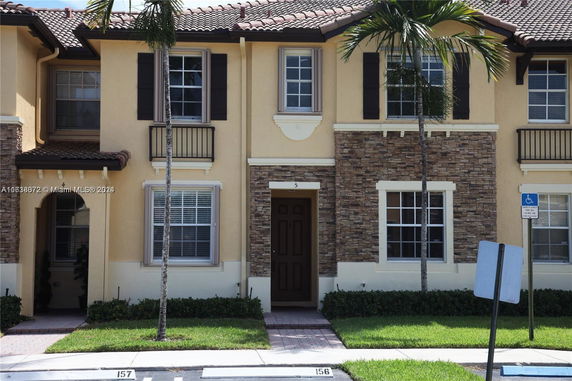 Front view of a two-story house with stone and stucco facade and a tile roof.