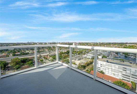 Panoramic view from a balcony overlooking an urban area with buildings and roads in the distance.