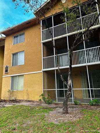 Front view of a multi-story building with screened balconies and yellow exterior walls.